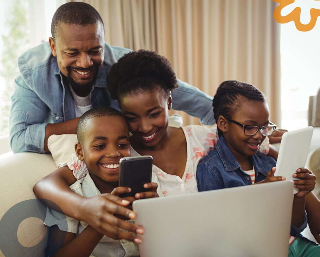 Family consisting of mum, dad and two foster children playing games on phone and laptops