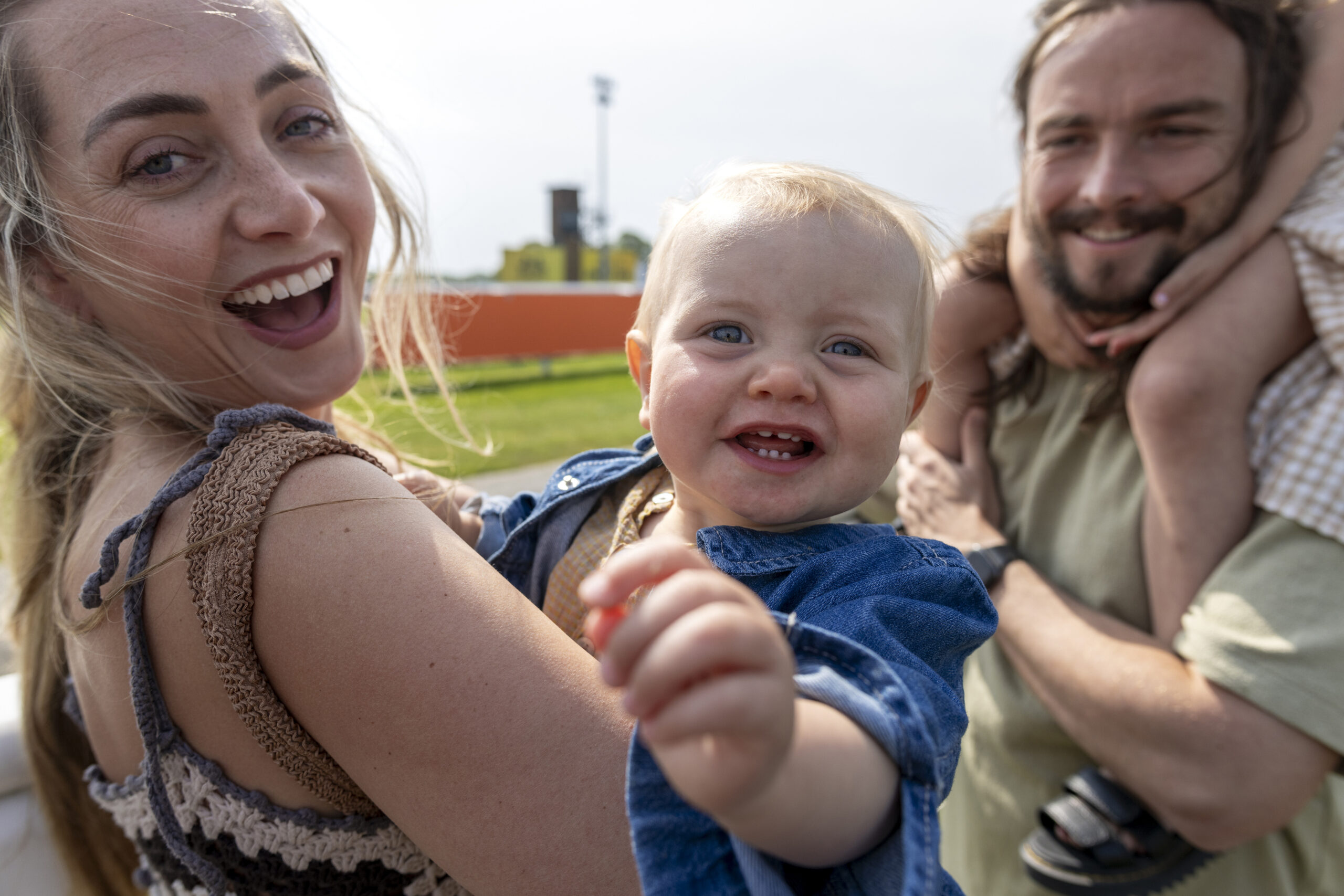 Close up of a foster family visiting an Easter fair at a racecourse in the North East of England. The foster carer is holding a baby, and they are both laughing at the camera.